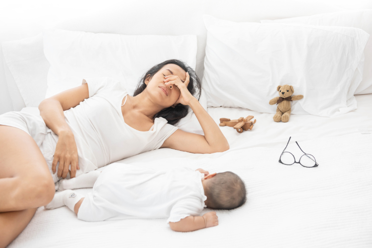 Exhousted mother with sleeping baby